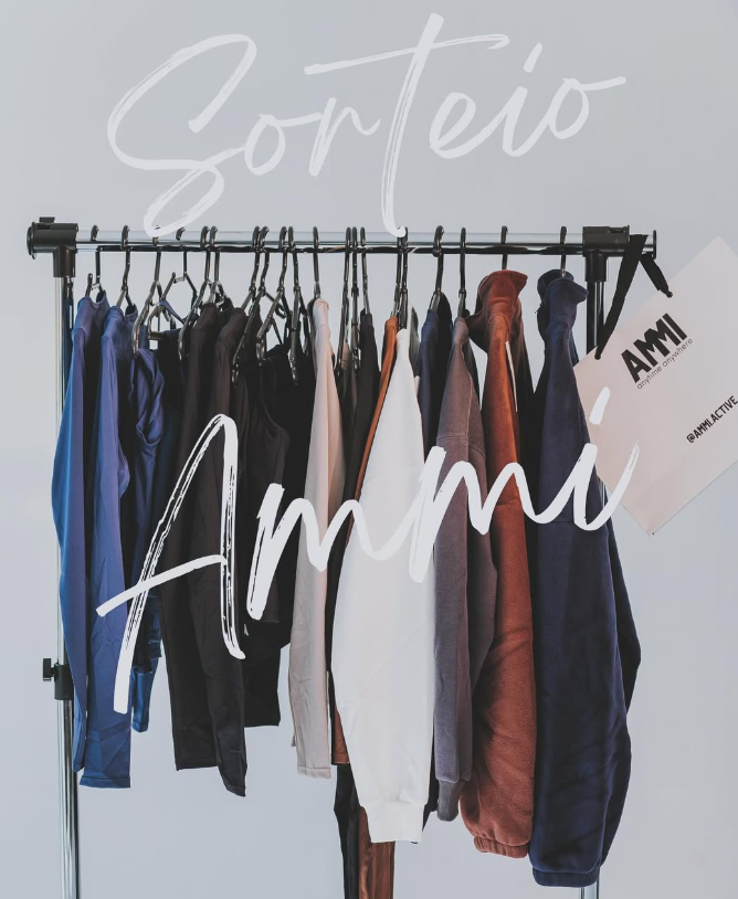 A clothing rack displaying various activewear pieces from AMMI, with a promotional sign that says "Sorteio" (giveaway), showcasing the brand's apparel collection.