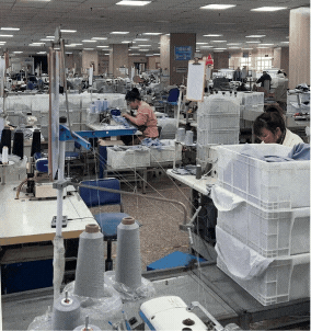 Workers in a sewing workshop at the activewear factory, showing multiple sewing machines and the garment production process.