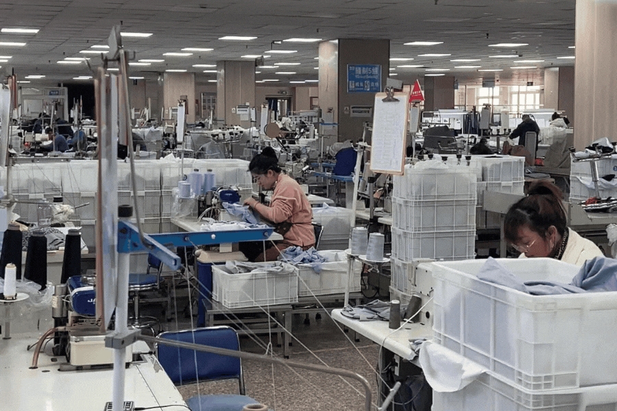 A view of a busy production line in a yoga apparel factory, with workers carefully assembling garments in a well-organized environment.