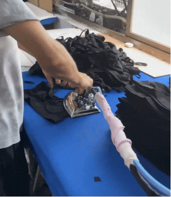 Worker ironing activewear pieces in Zi Yang factory, showcasing the final step in the manufacturing process.