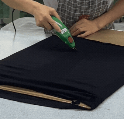 Worker sealing fabric for activewear shorts using a heat press at Zi Yang factory, showcasing part of the manufacturing process.