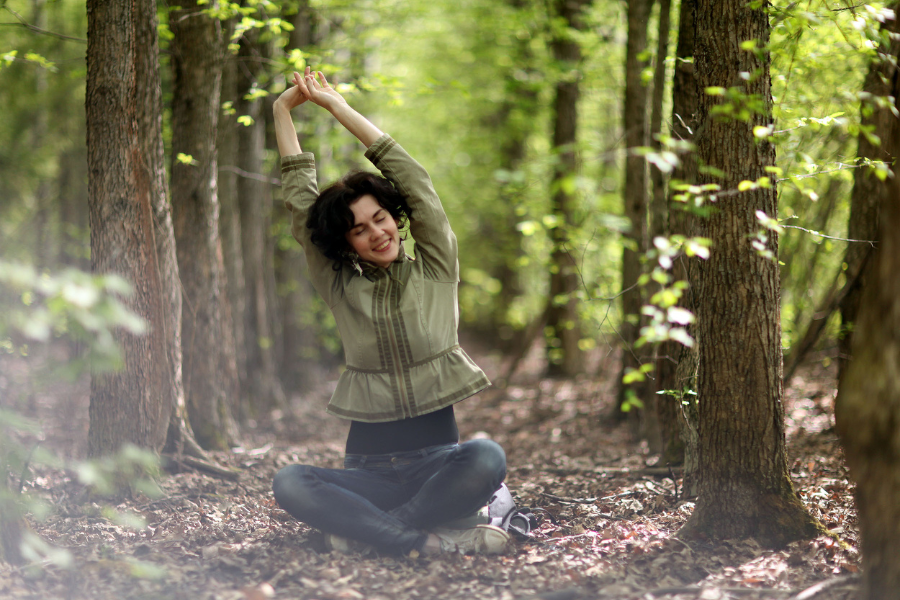 A woman stretching outdoors in a forest, embodying a yoga lifestyle with nature.